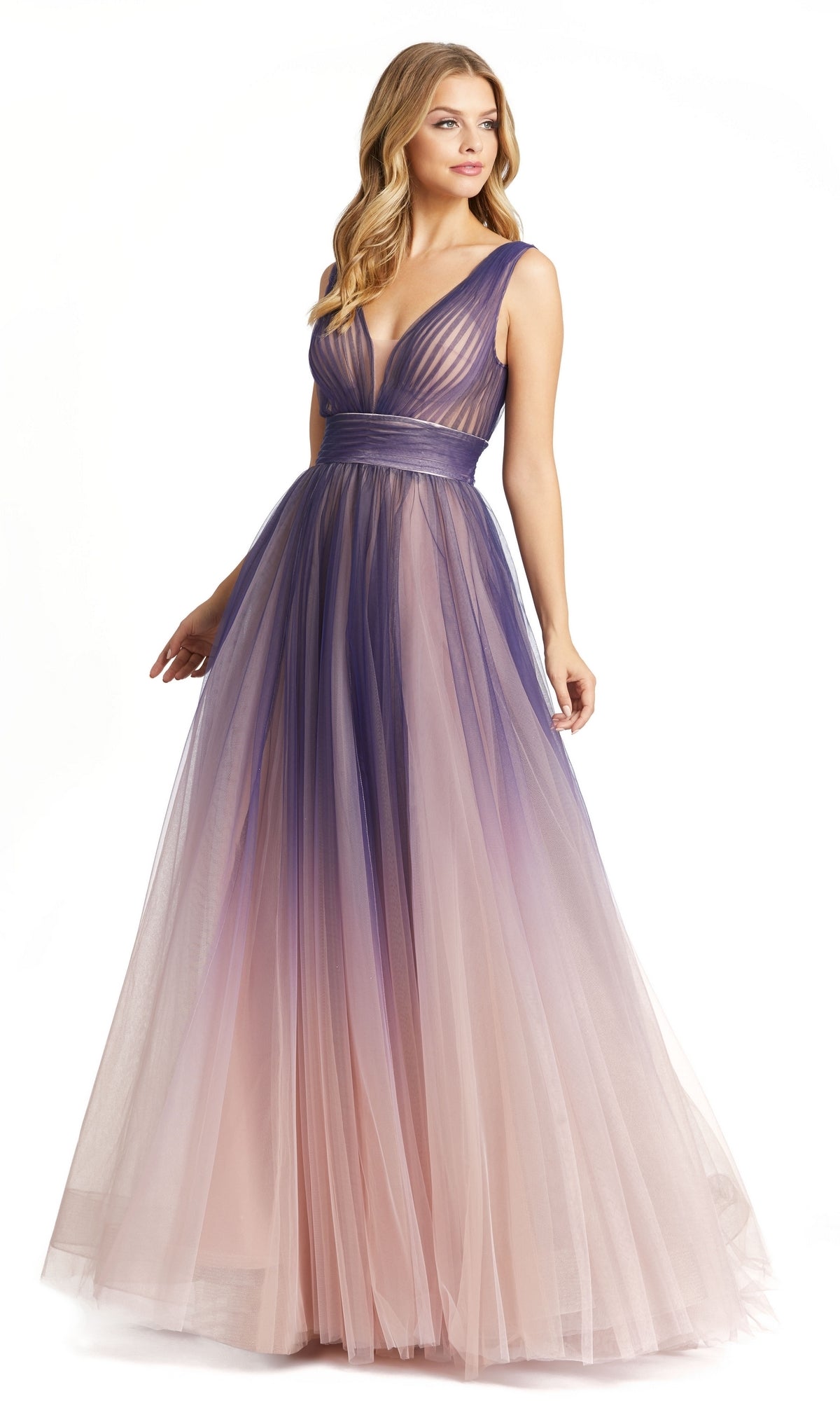 A woman wears the Mac Duggal 20221 Indigo Ombre Prom Ball Gown—a sleeveless, floor-length tulle dress with a deep V-neckline featuring a gradient from indigo to light pink.